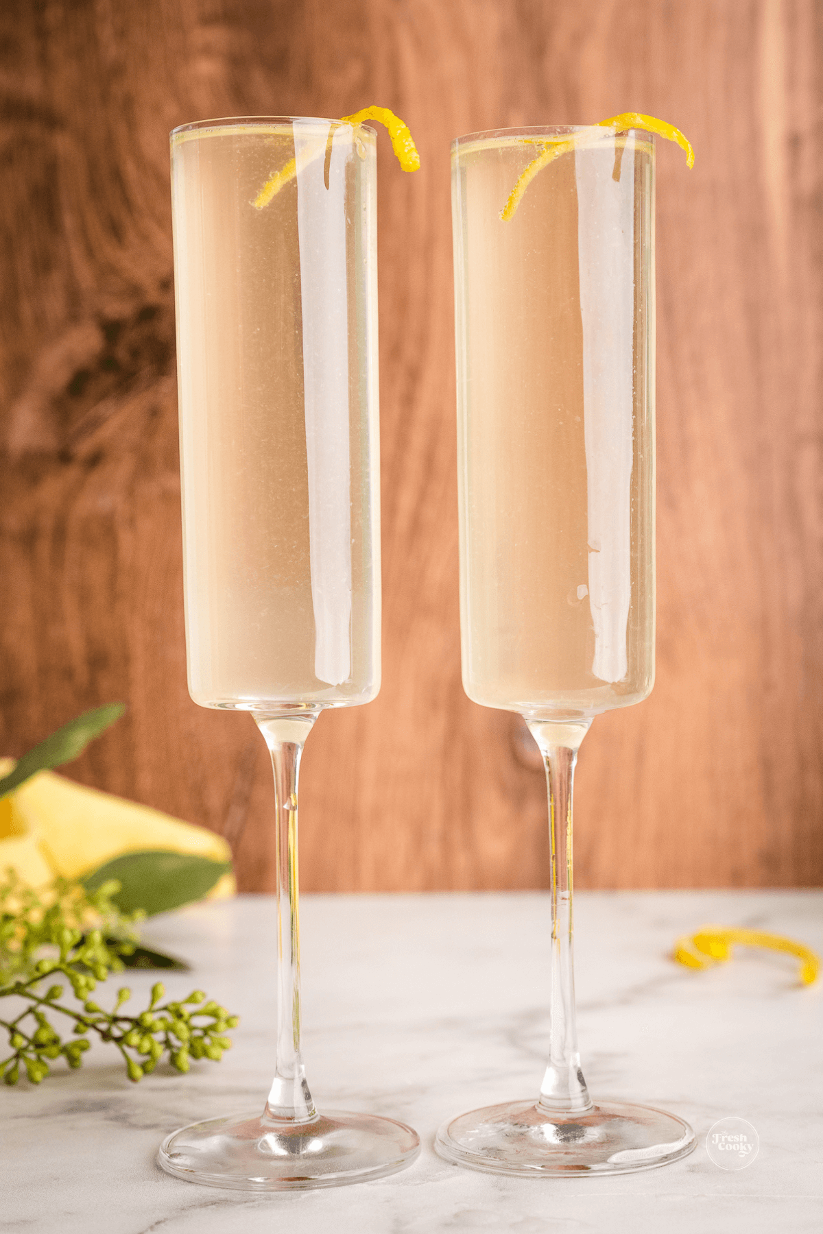 Gorgeous champagne flutes filled with French 75 recipe with St Germain and a lemon twist.