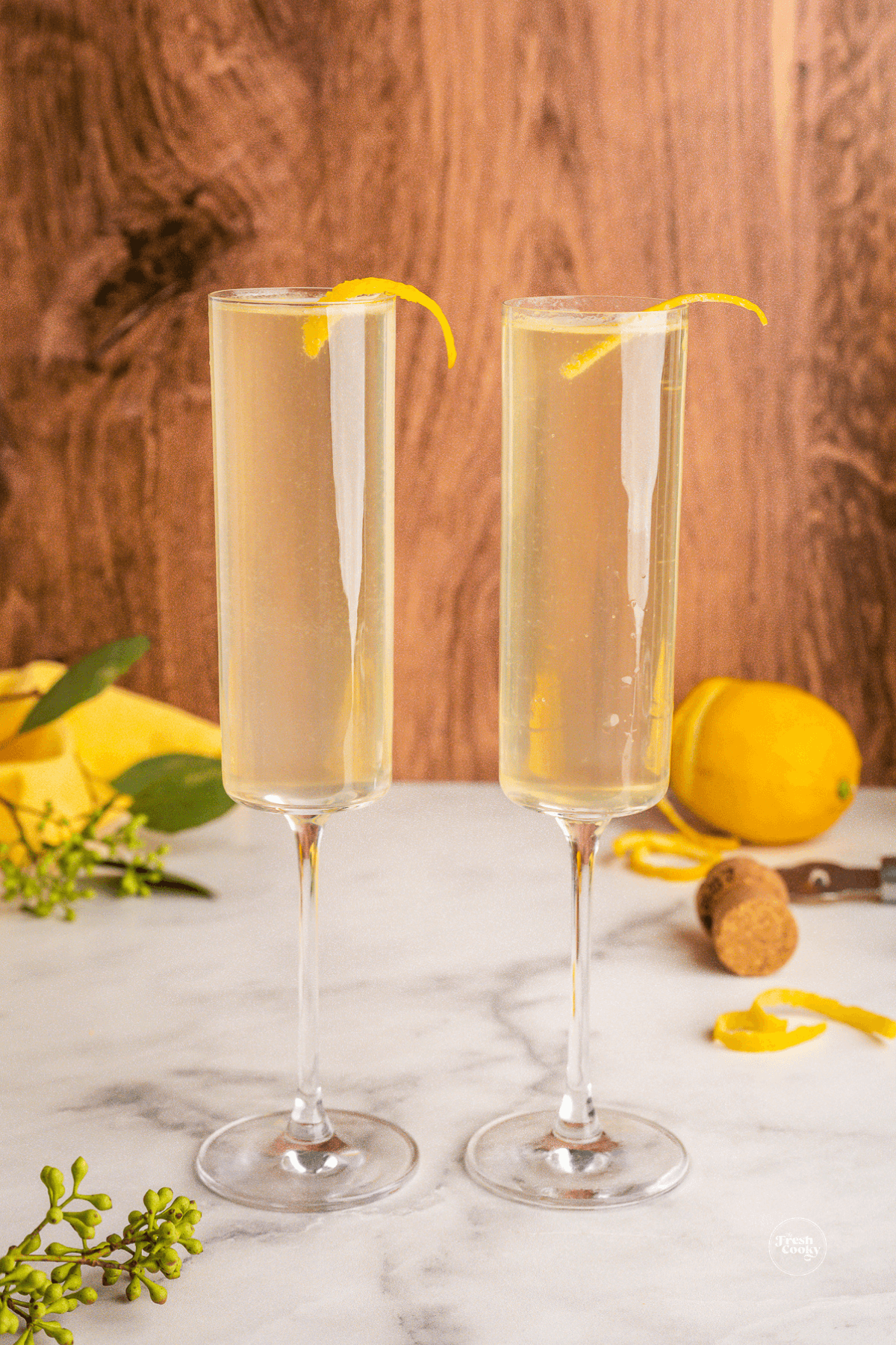 Two glasses of French 75 elderflower cocktail, with lemon twist.