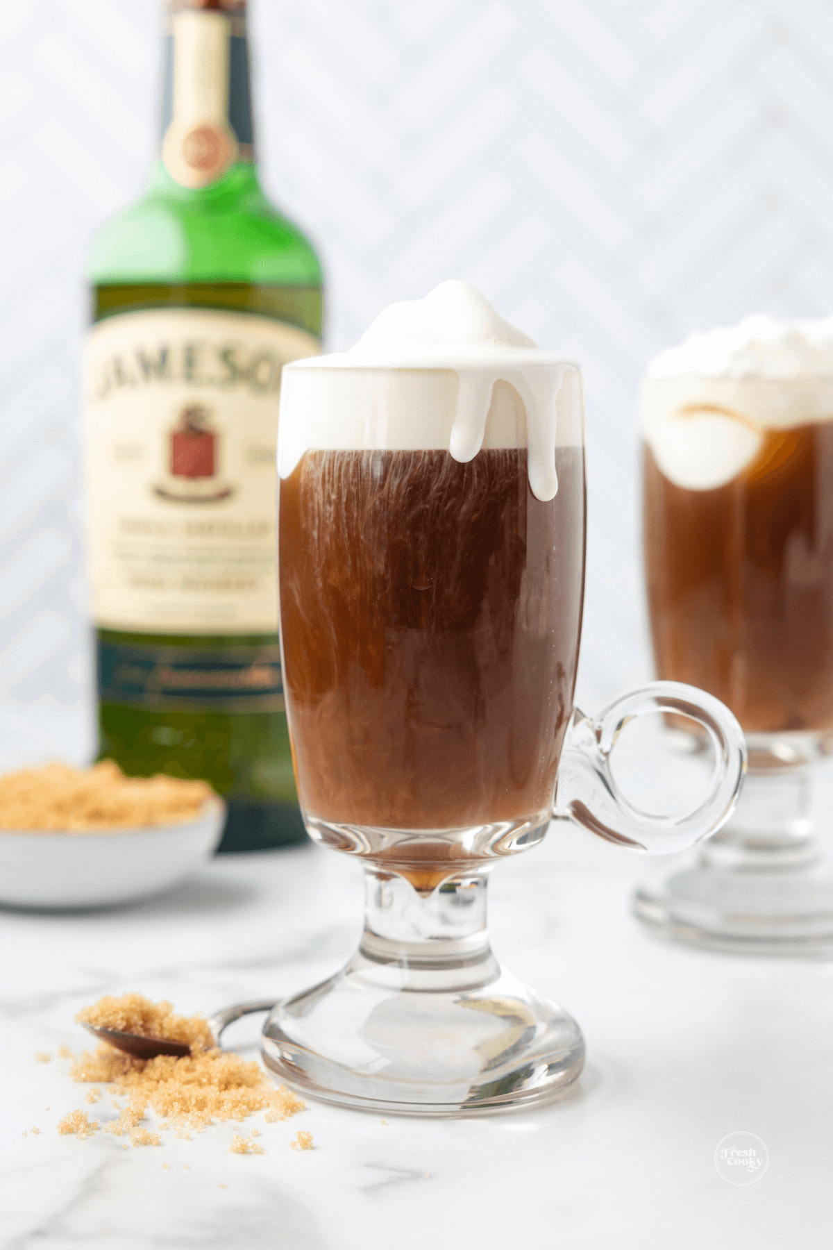 Mugs of Irish coffee with Irish whiskey in the background.