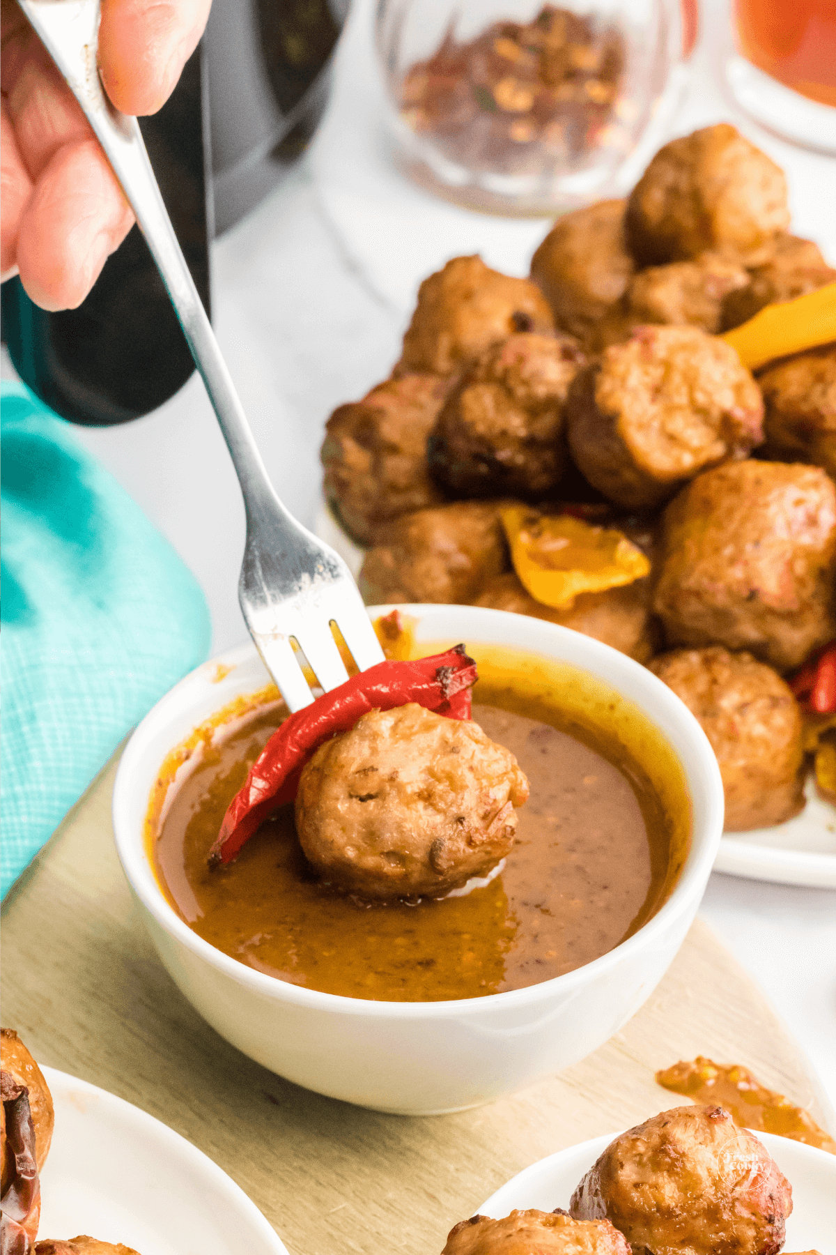 Italian sausage bite being dipped into spicy ale mustard sauce.