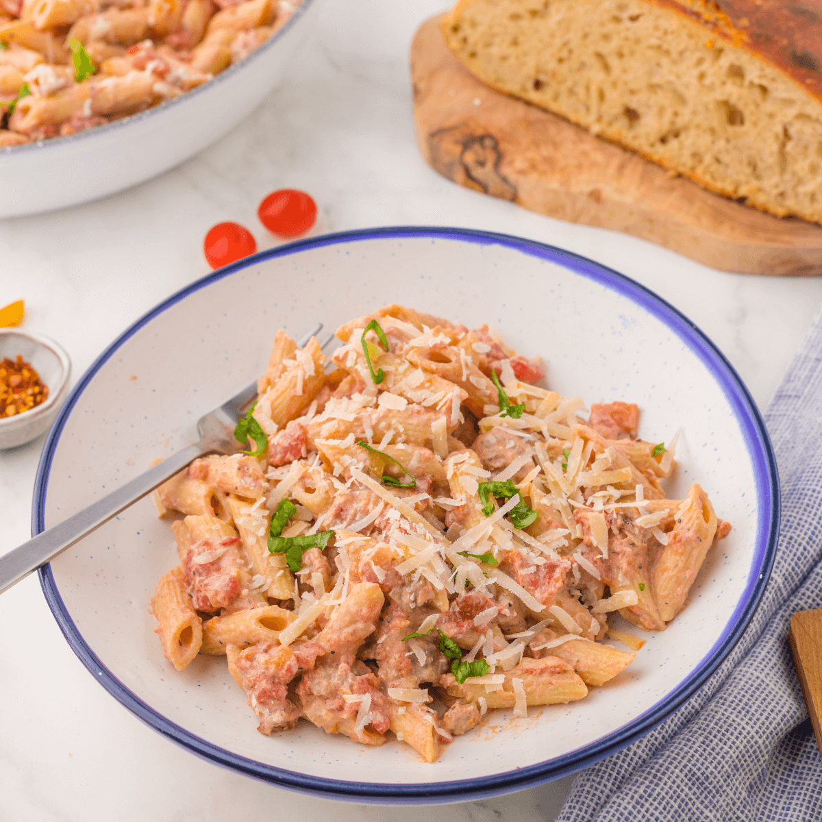 One pot creamy sausage pasta in bowl with bread in background.