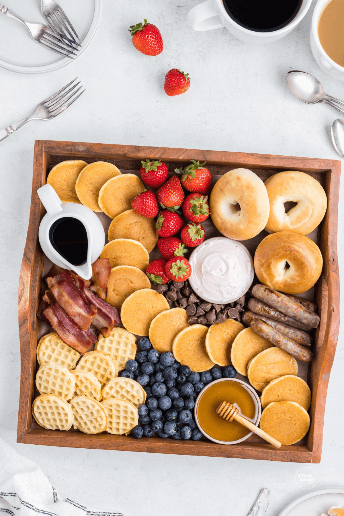 Pancake breakfast charcuterie board with air fryer sausages, bacon, waffles, fresh fruit and toppings.