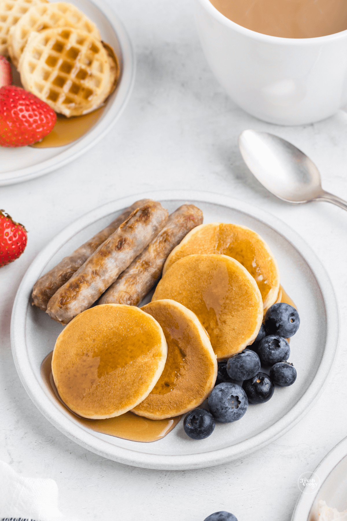 Pancakes and waffles with sausage and berries on a plate, from breakfast charcuterie board.