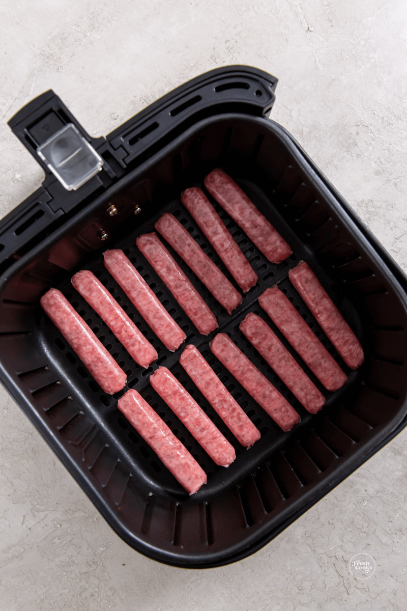 Air fryer with raw link sausage ready to cook. 