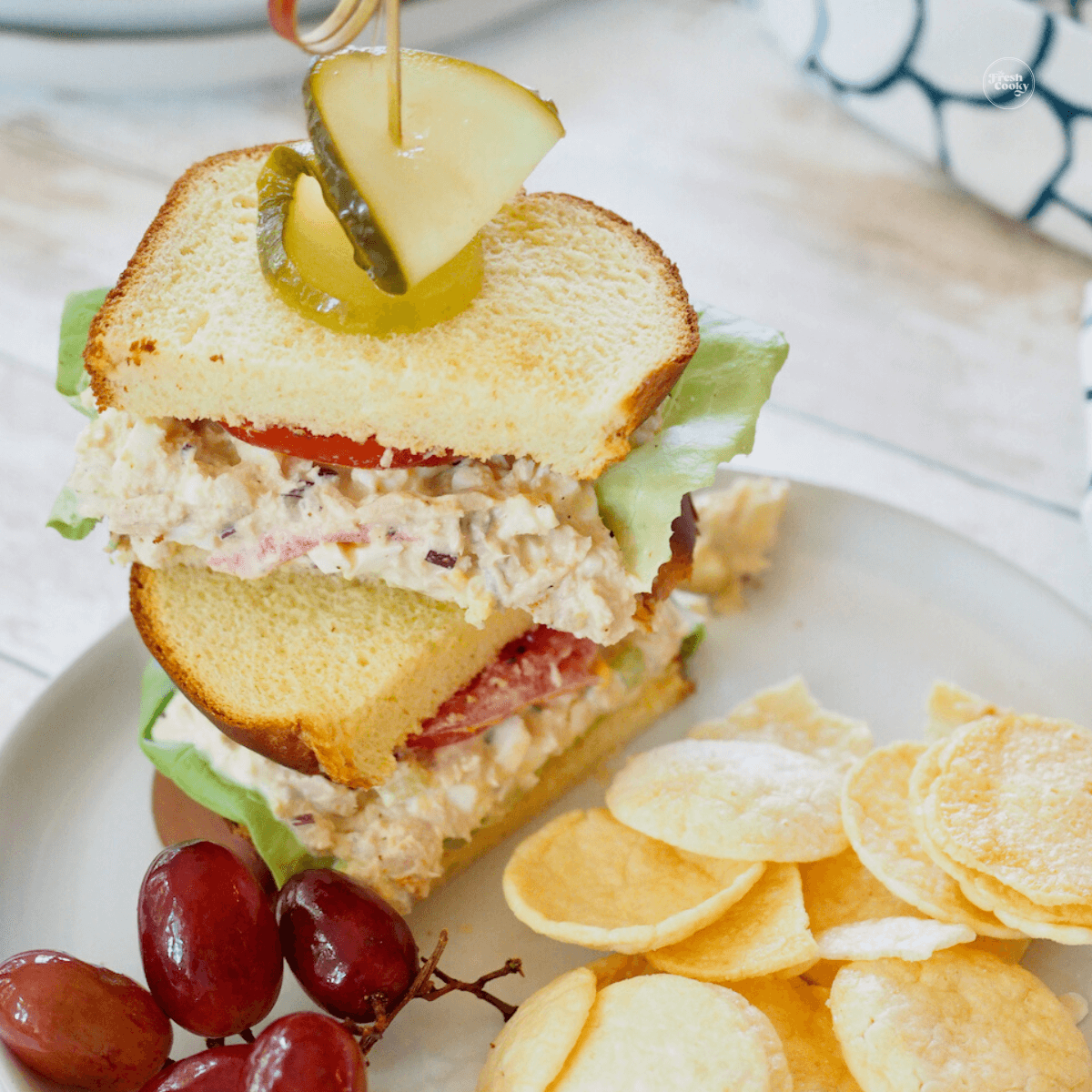 Southern Tuna Salad recipe on sandwich brioche bread, with chips and grapes.