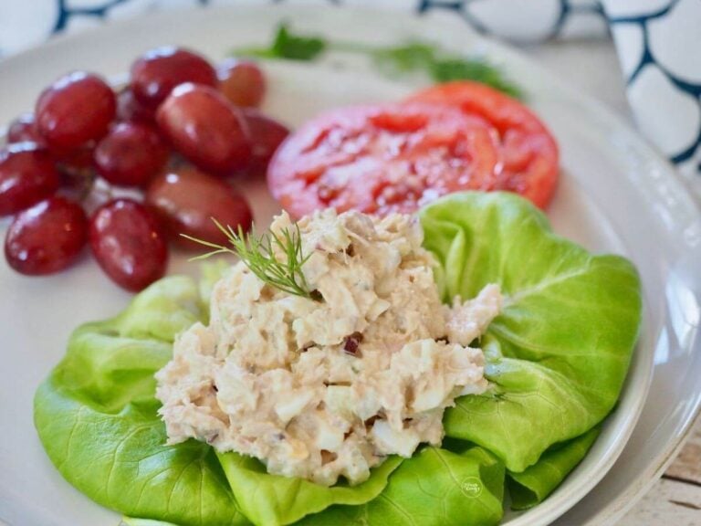 Scoop of Southern tuna salad on butter lettuce with sliced beefsteak tomatoes and grapes.