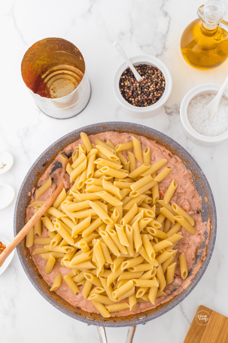 Stirring pasta into sauce. 