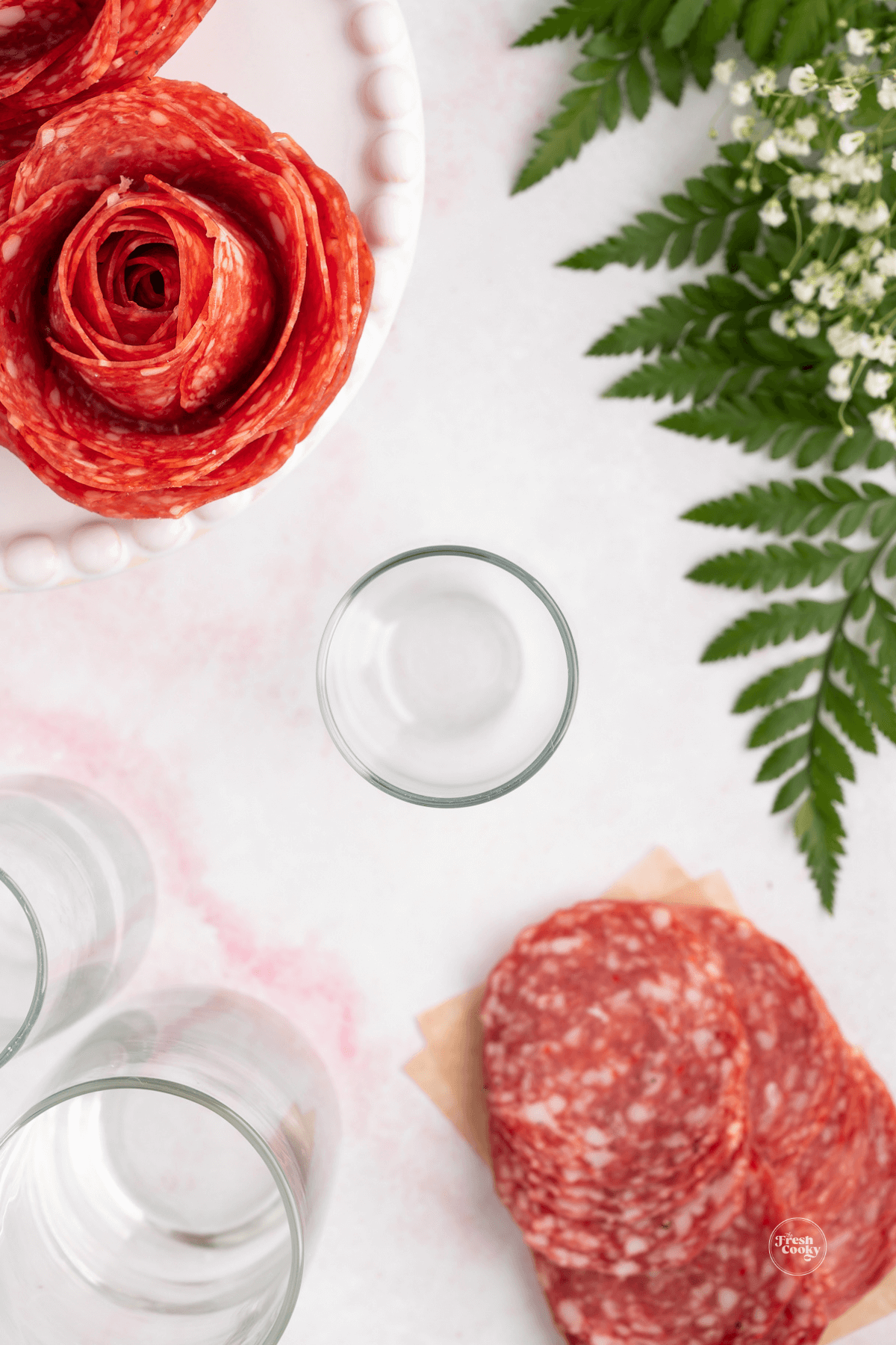 Champagne flute with salami nearby to make salami rose.