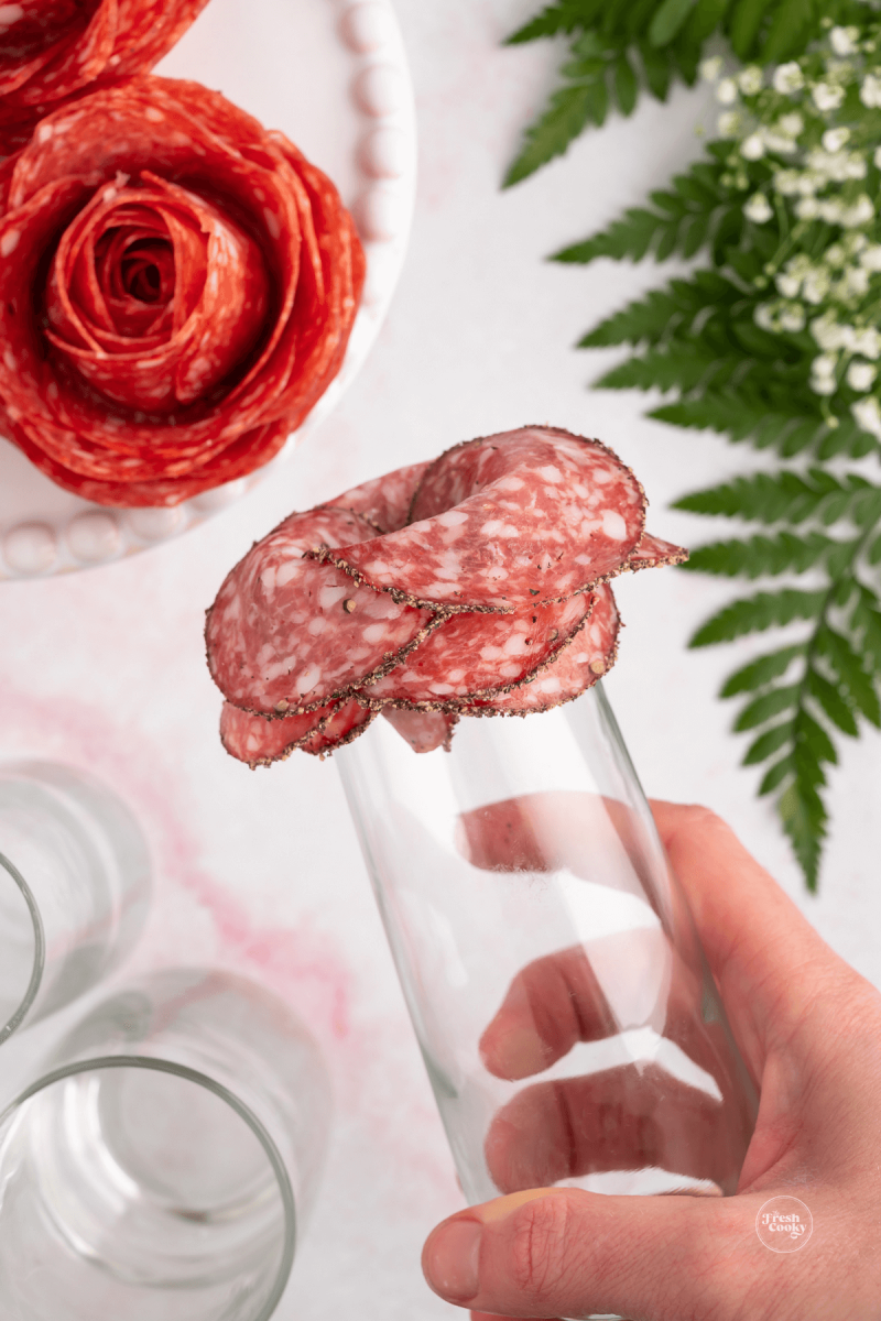 Inverting glass with salami on it to make salami roses. 