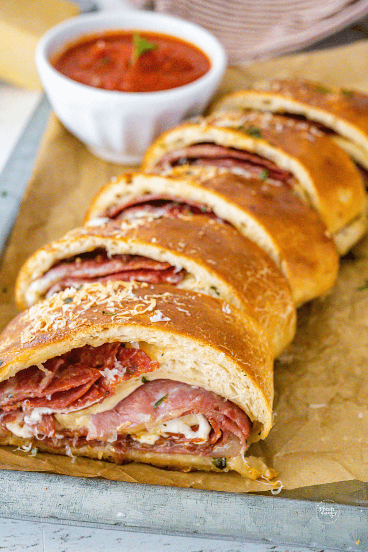 Slices of stromboli on tray with small bowl of dipping pizza sauce.