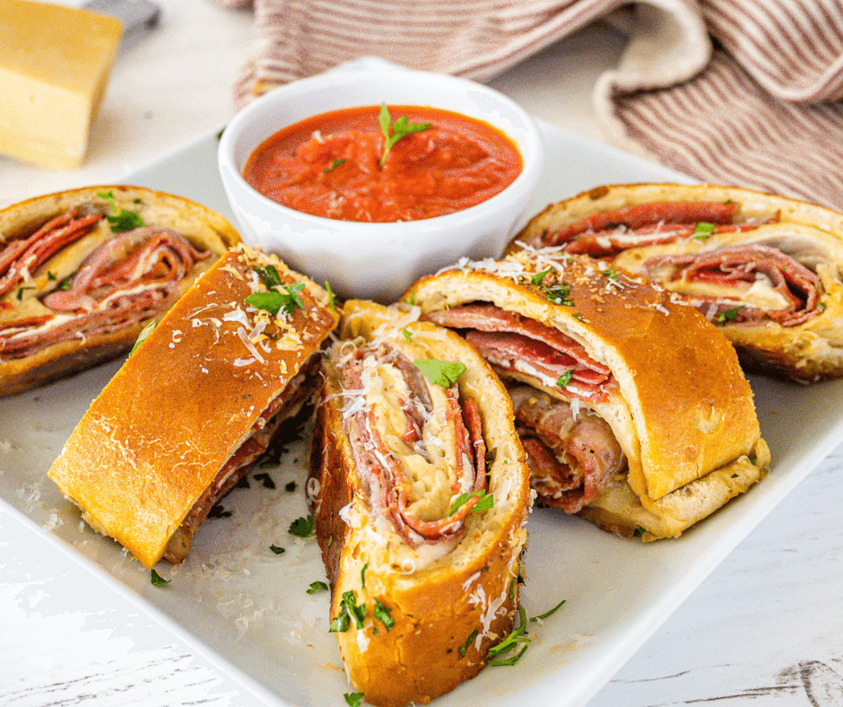 Stromboli slices on platter with bowl of marinara dipping sauce.
