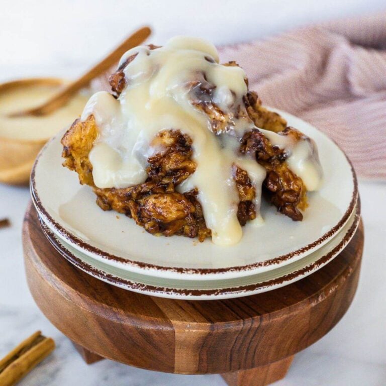 Cinnamon roll casserole serving topped with frosting on a plate.