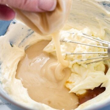 Squeezing packet of frosting into butter and cream cheese for frosting.