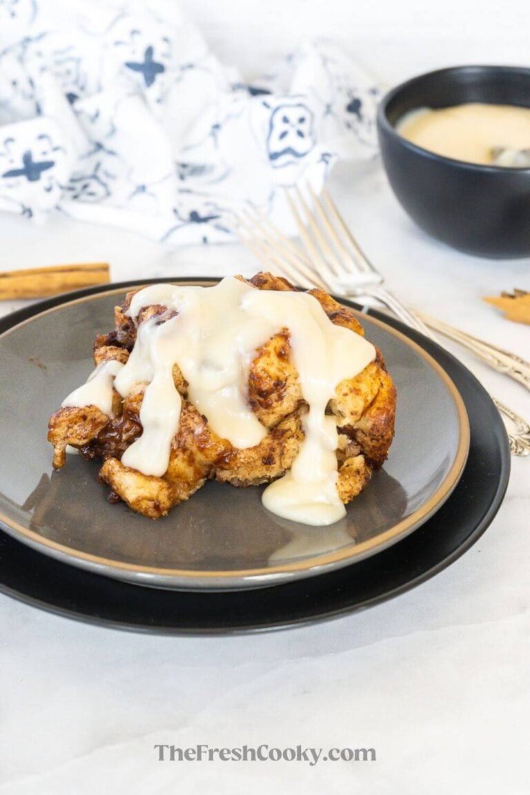 A serving of crock pot cinnamon roll casserole smothered in frosting, for pinning.