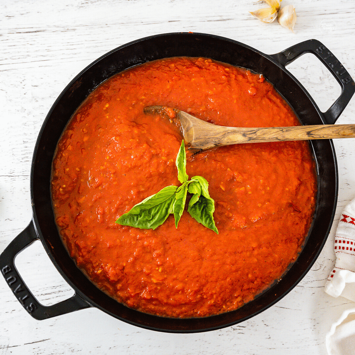 Pan filled with Italian marinara sauce topped with fresh basil.