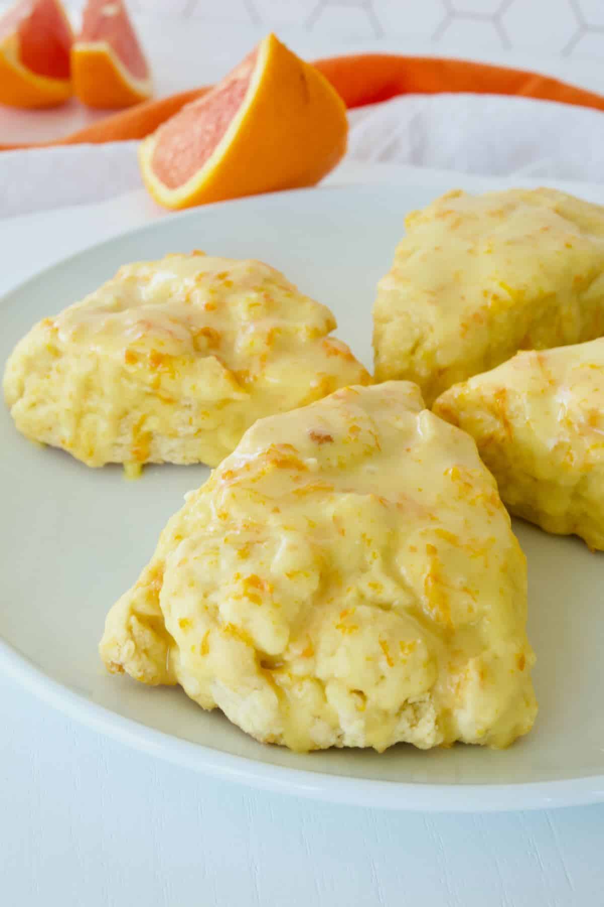 Four orange glazed scones on a pretty plate.