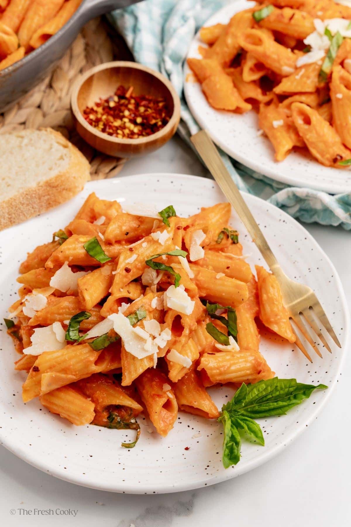 A couple of plates of penne alla vodka sprinkled with cheese. 