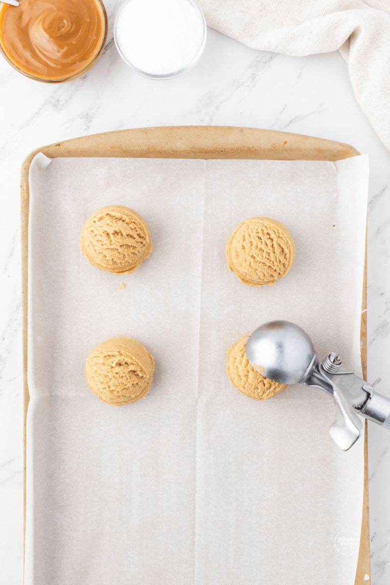 Using large cookie scoop scoop heaping dough balls onto cookie sheet, roll in graham cracker crumbs for salted caramel cookies. 