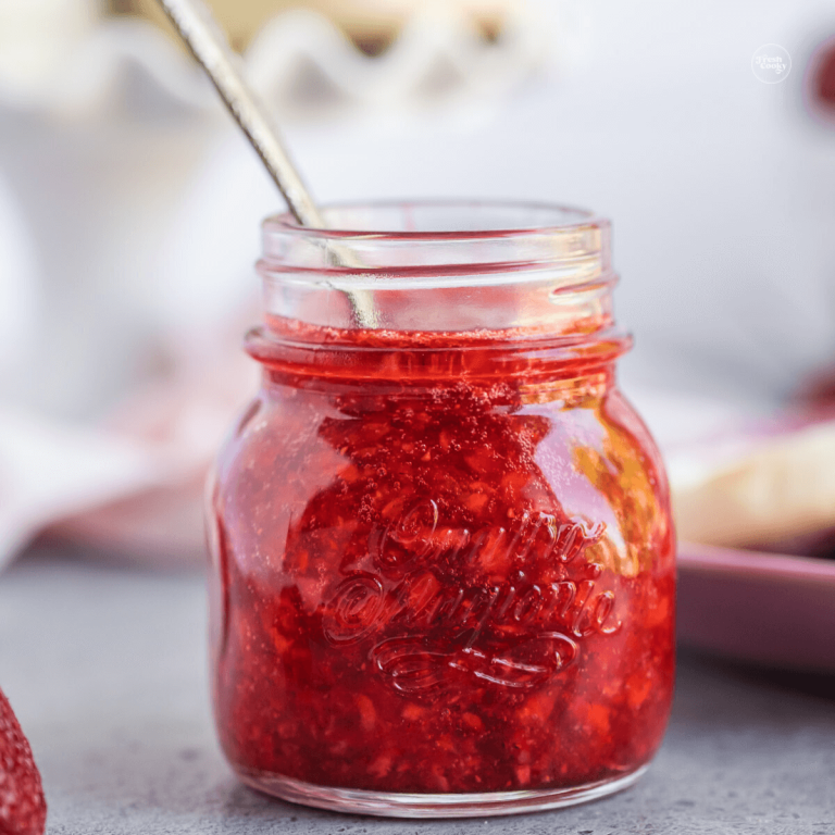 Strawberry Freezer jam in a pretty jar with a spoon inside.