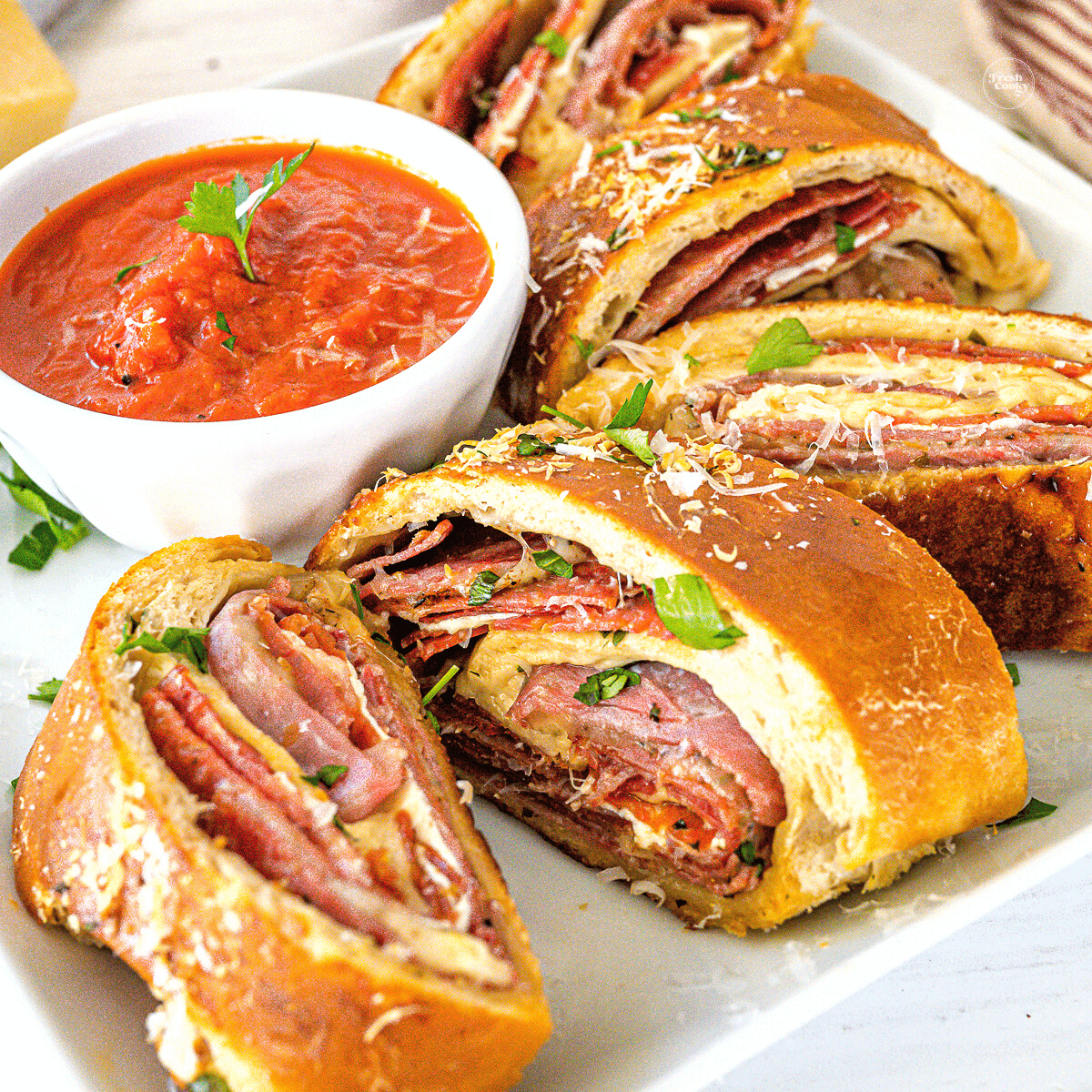 Authentic Italian Stromboli recipe, slices on plate with marinara sauce.