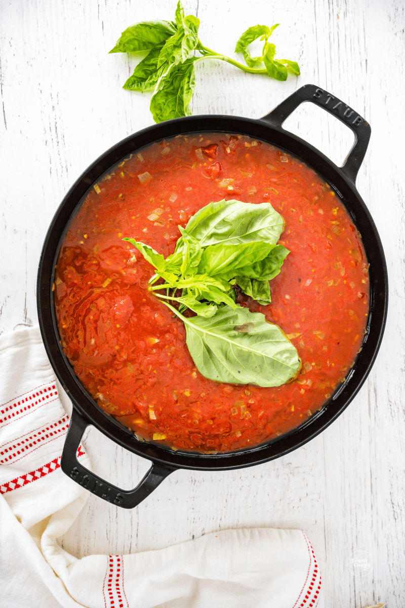 Add basil to the top of the pan, let it wilt into the sauce.