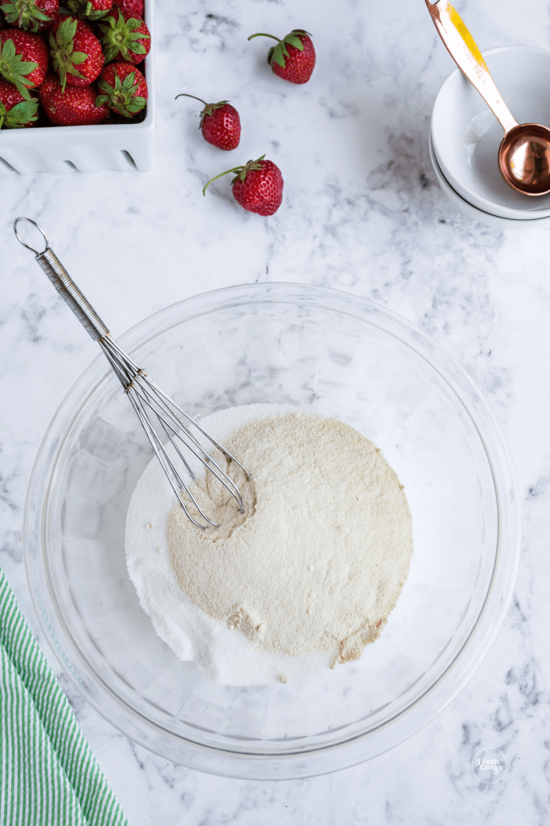 Fruit pectin and sugar in bowl with whisk for low sugar strawberry freezer jam. 