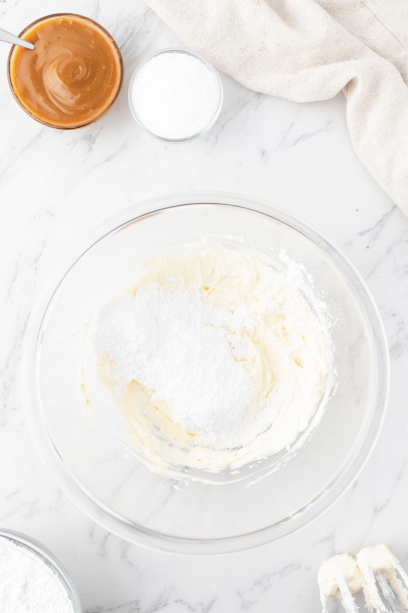 Add powdered sugar to cheesecake frosting. 