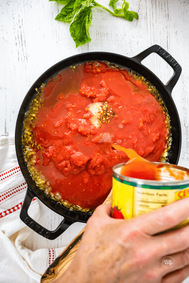 Pour tomato water into sauce, rinsing out can. 
