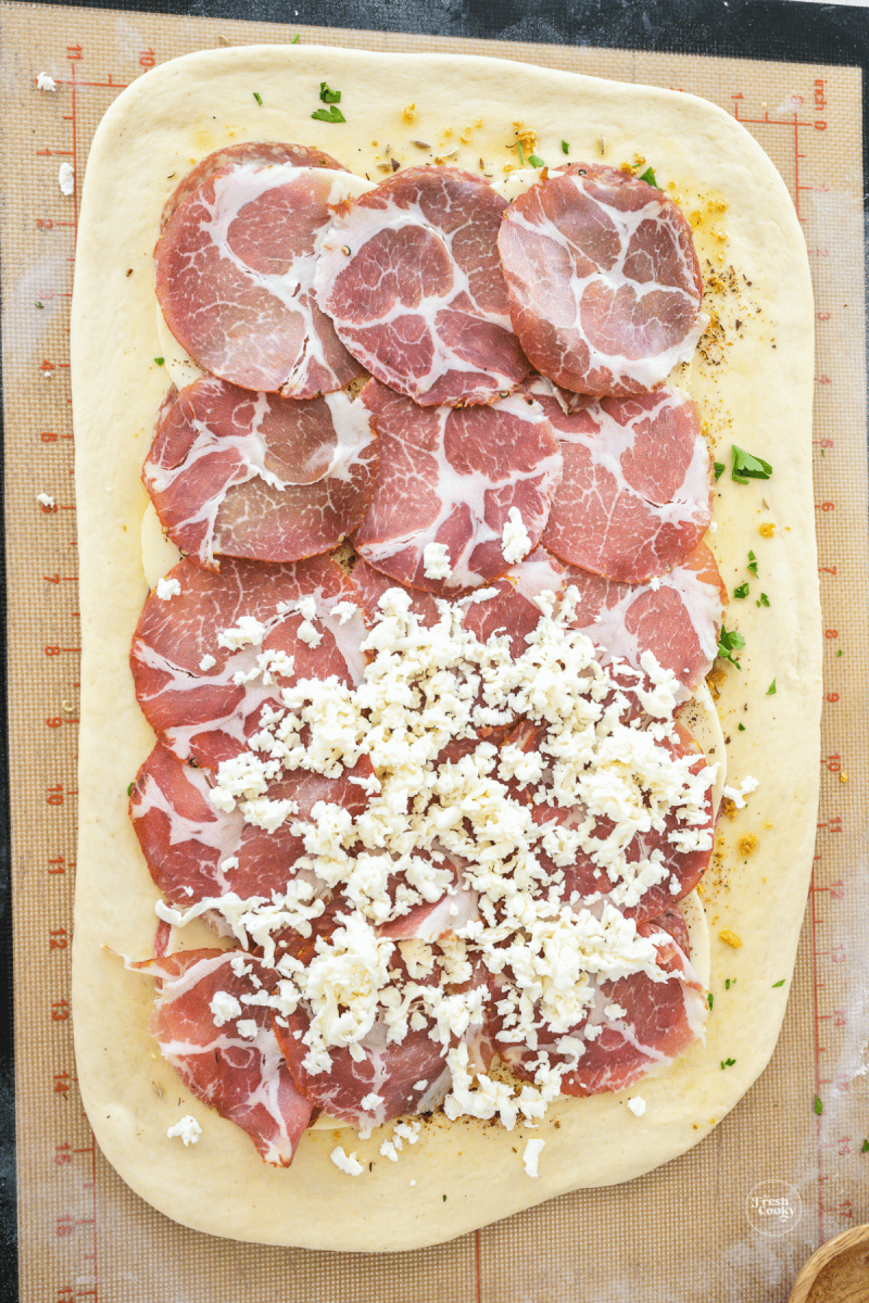 Capicola topped with mozzarella cheese for layer in stromboli.