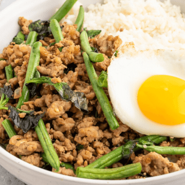 Ground pork stir fry with green beans, Thai basil and a Thai fried egg in a bowl, for Facebook.