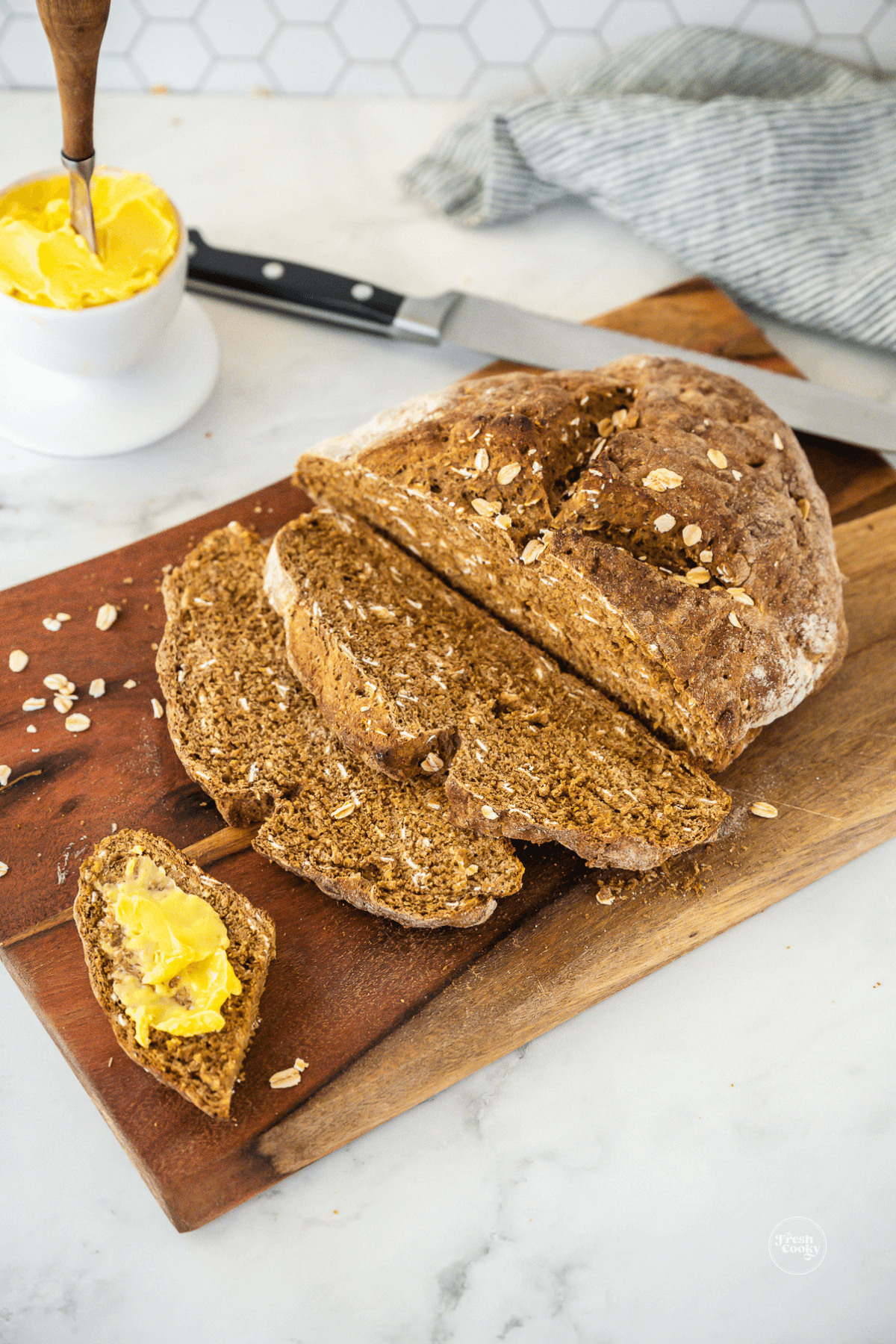 Loaf of Authentic Irish brown bread recipe sliced with a piece buttered with Irish butter.