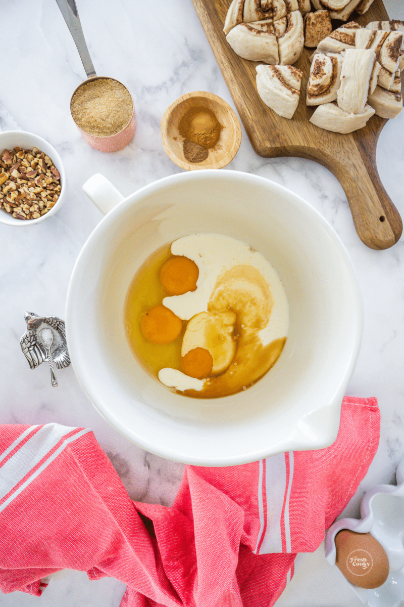 Eggs, heavy cream and vanilla in mixing bowl for cinnamon roll casserole. 