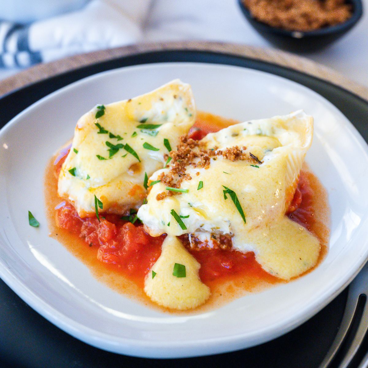 Olive garden stuffed shells on a plate with a drizzle of Alfredo sauce.