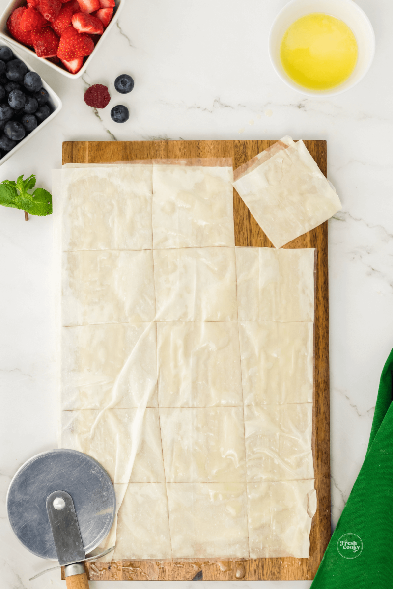 Cutting phyllo dough pastry into squares for phyllo cups. 