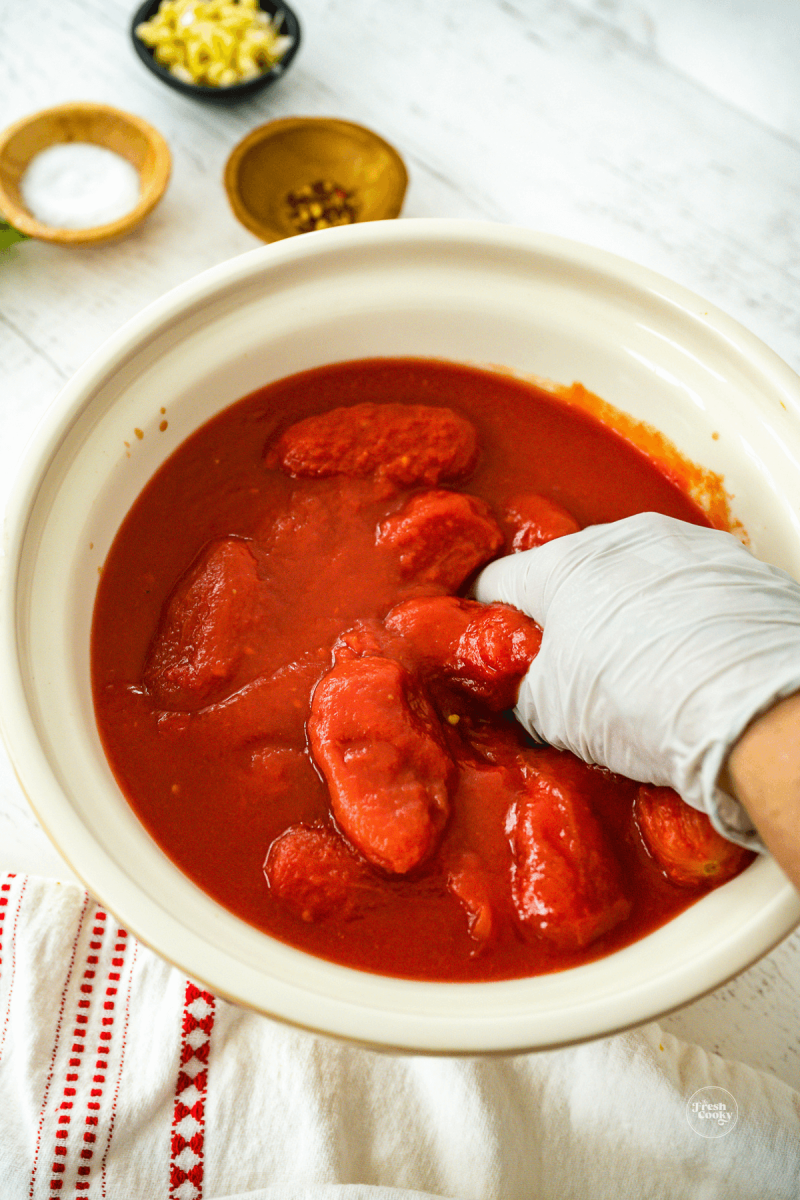 In a large bowl squeezing tomatoes and crushing for the recipe.