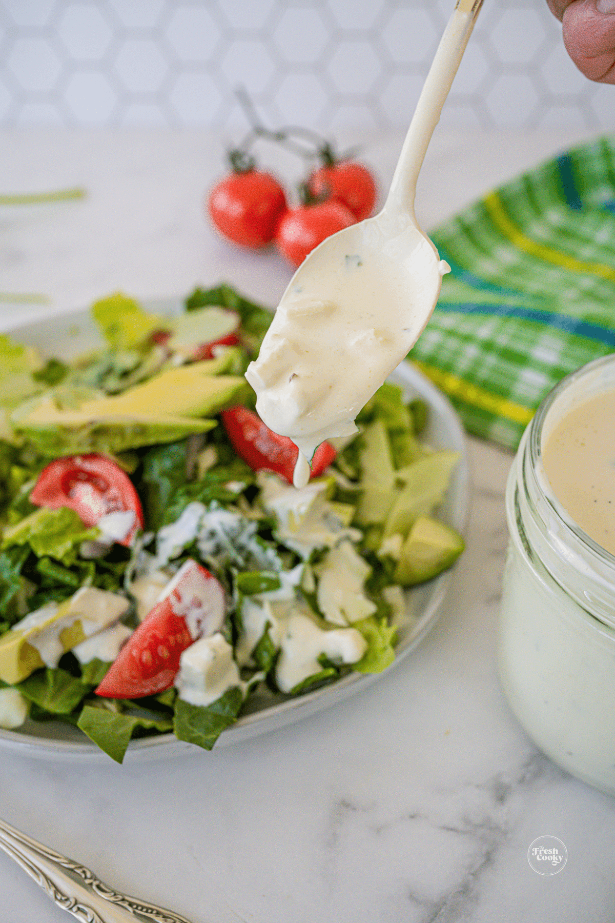 Drizzling blue cheese dressing onto a fresh salad.