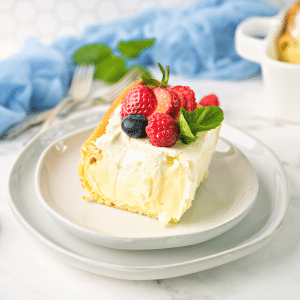 Slice of cream puff cake topped with fresh berries and a sprig of mint.