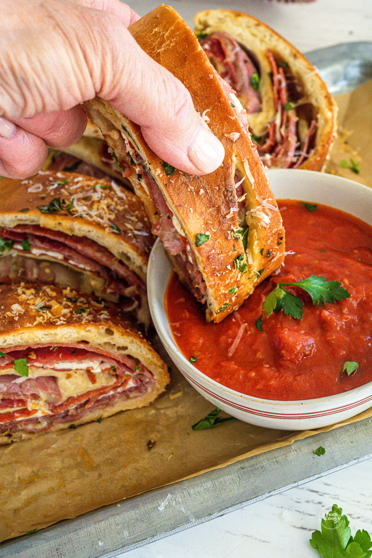 Stromboli slice being dipped into marinara sauce.