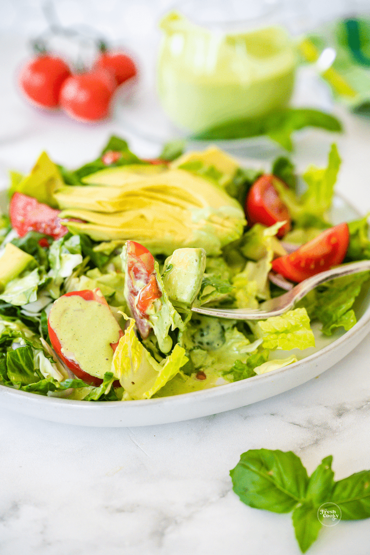 Green goddess dressing poured onto a crisp green salad.