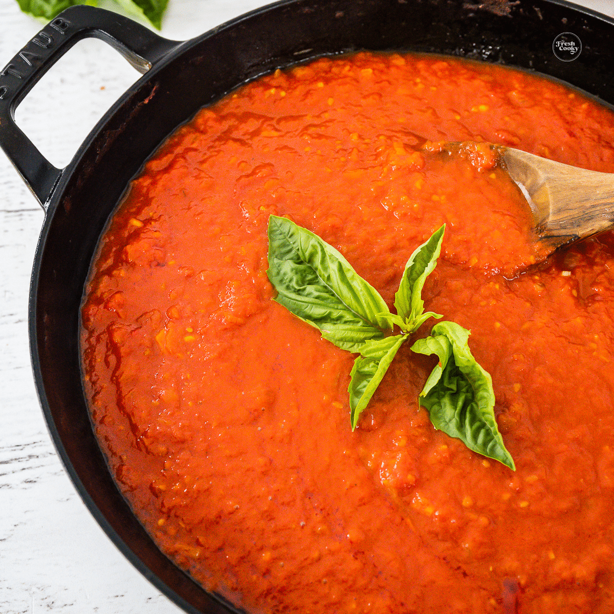 Pan filled with marinara sauce and topped with sweet basil.