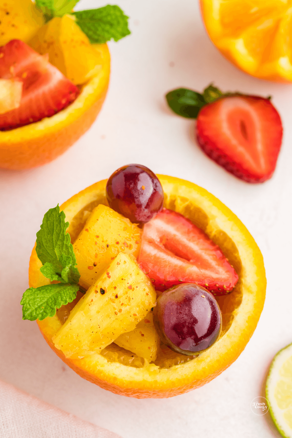 Mexican fruit cups garnished with tajin and a sprig of mint.