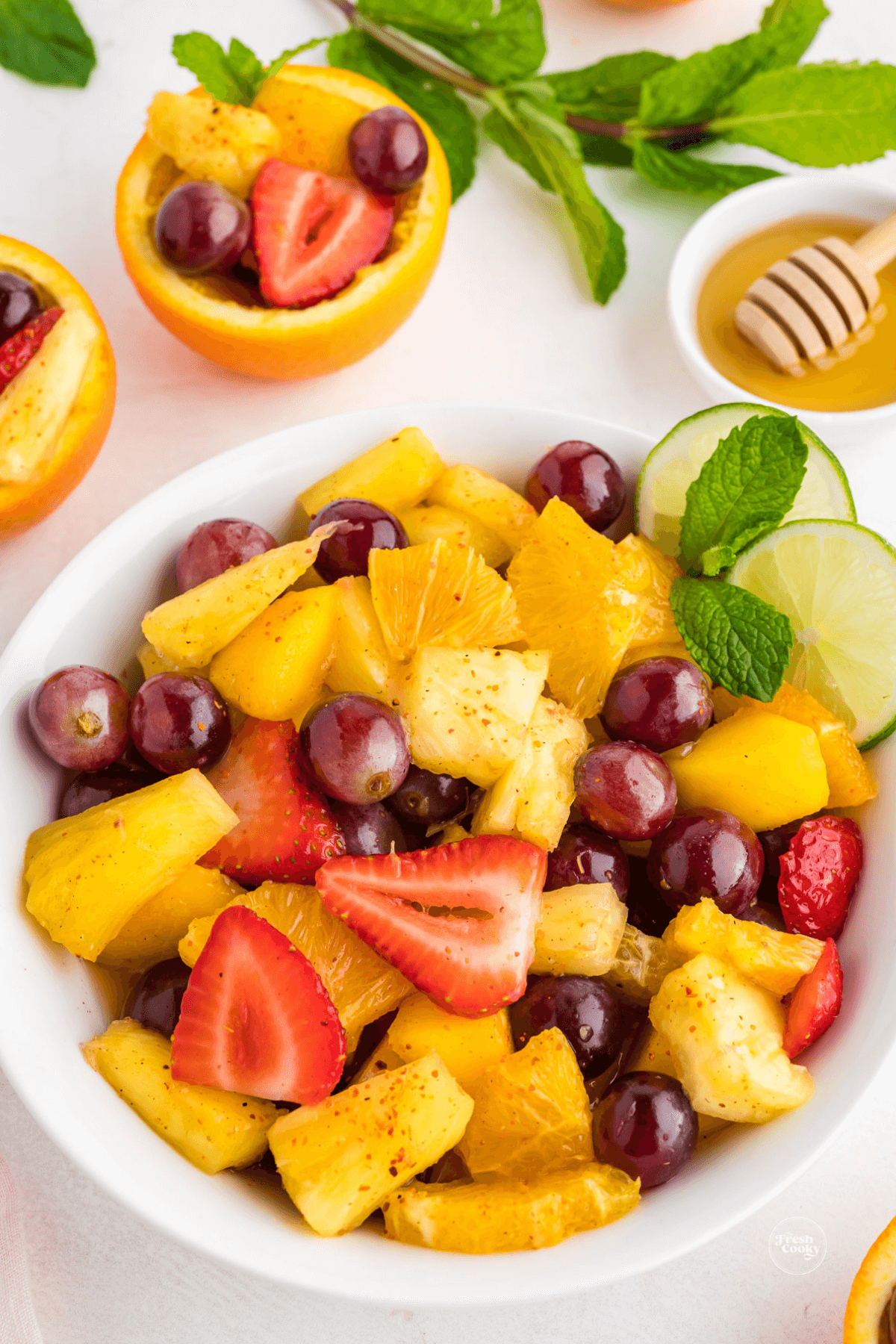 Fresh Mexican Fruit Salad recipe in bowl with single servings in fruit cups behind.