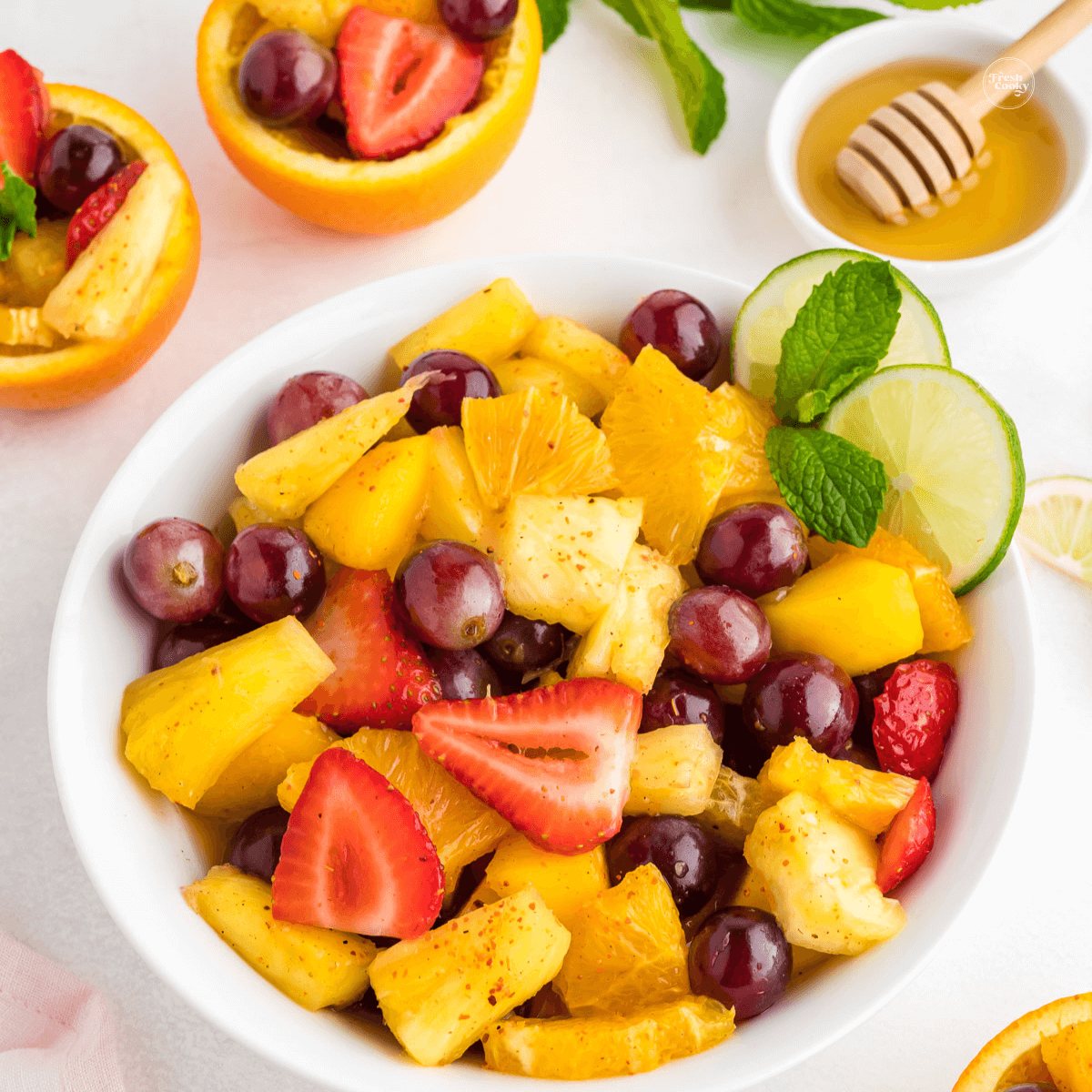 Easy Mexican Fruit salad in serving bowl and fruit salad served in orange fruit cups.