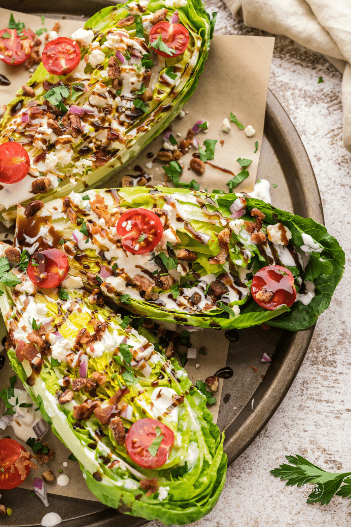 Romaine wedge salads on a platter sprinkled with all the good toppings.