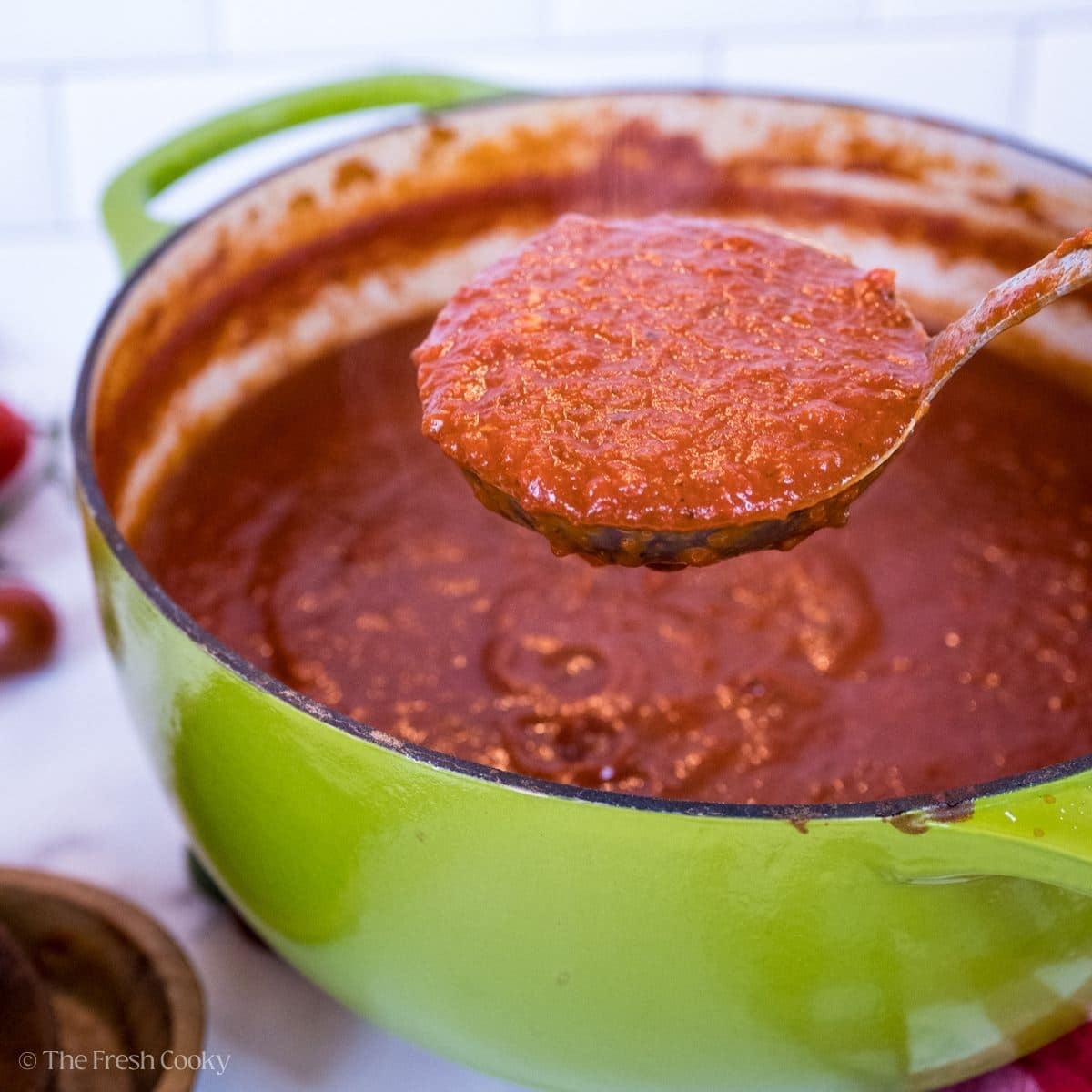 Rich and thick spaghetti sauce being ladled out of a Dutch oven.