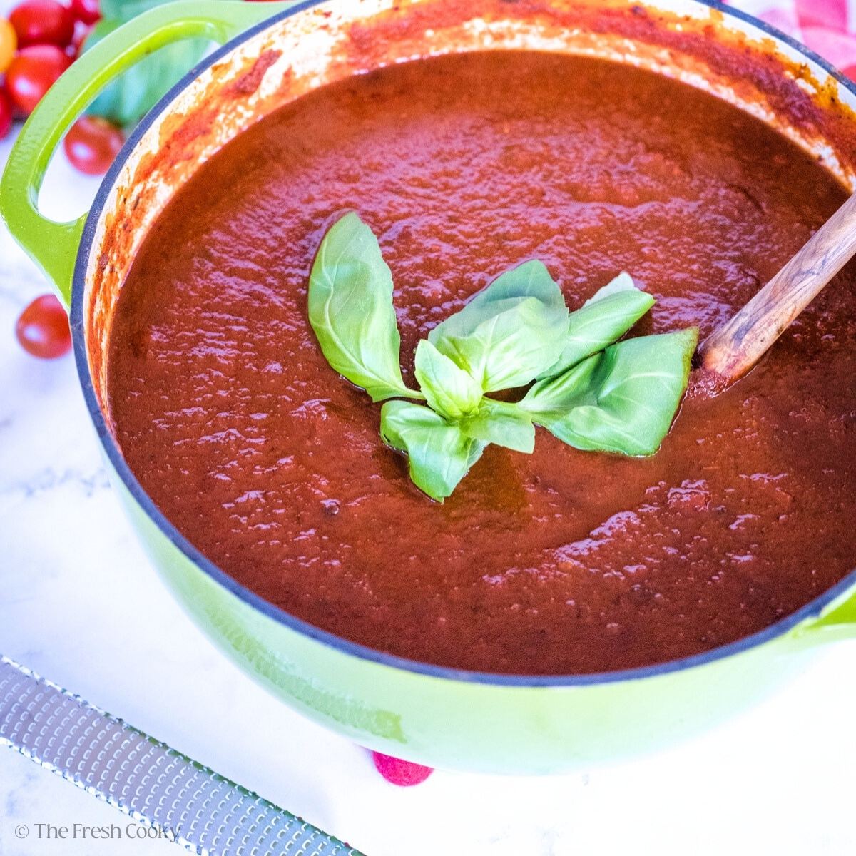 Dutch oven filled with rich, dark spaghetti sauce, topped with fresh basil.