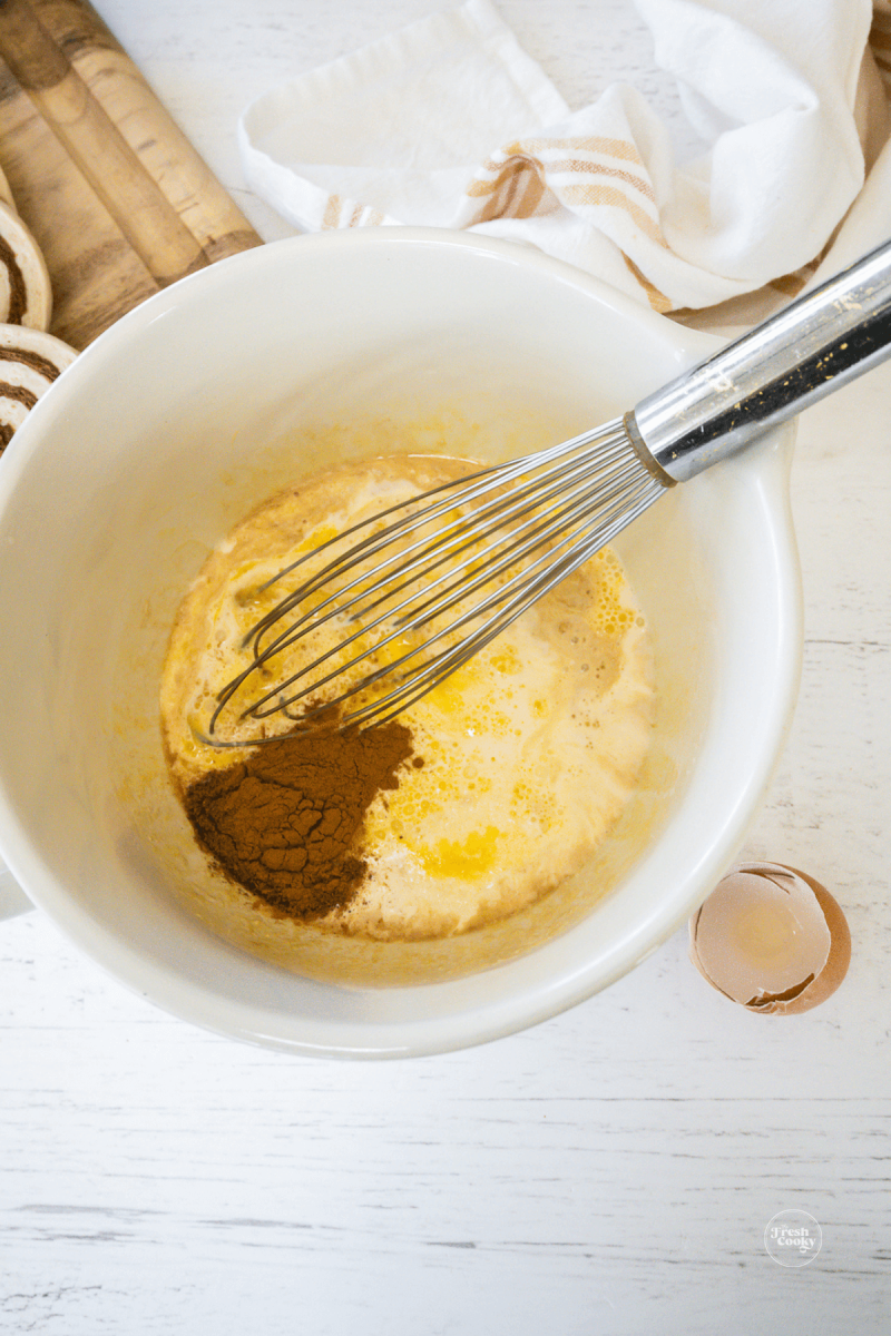 Whisk eggs, cream and spices together for cinnamon roll casserole.