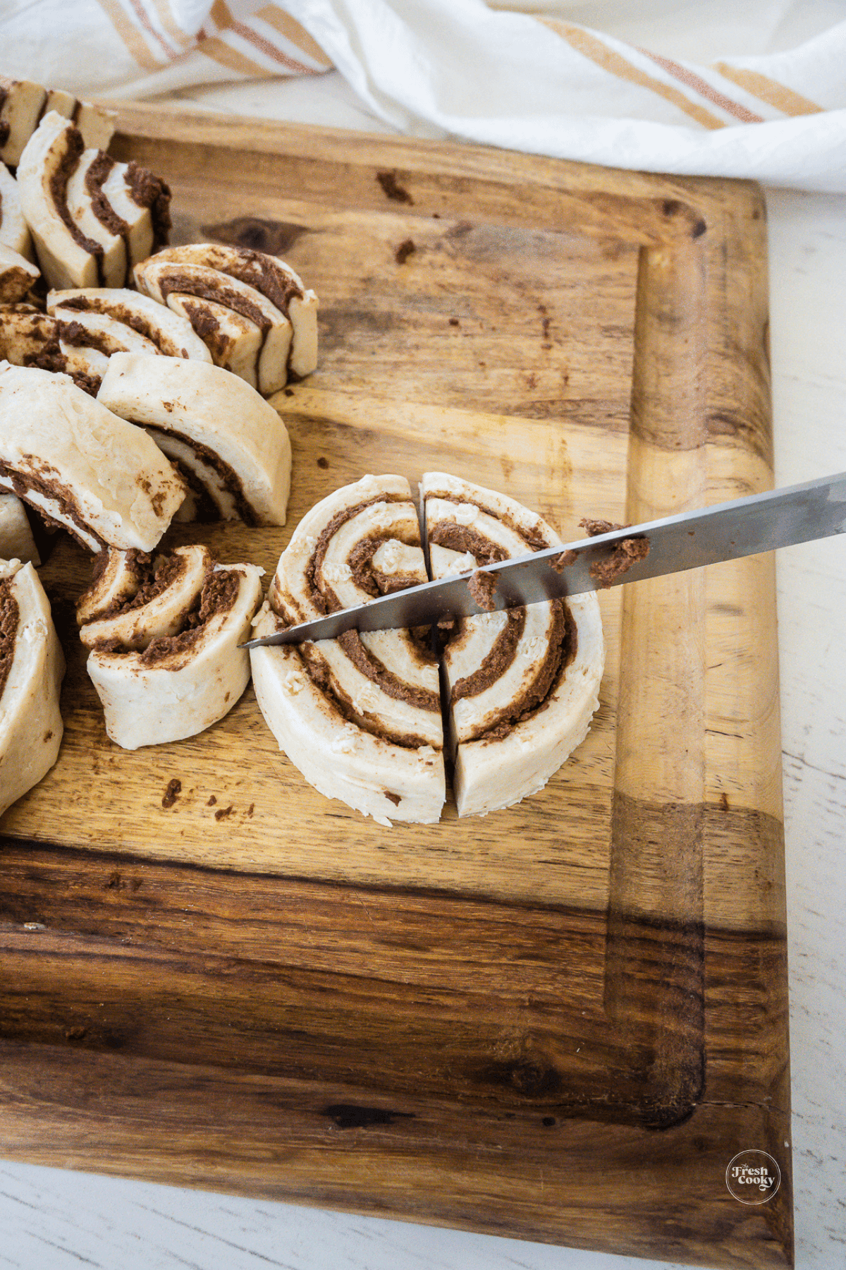 Cutting cinnamon rolls into quarters for cinnamon roll casserole.