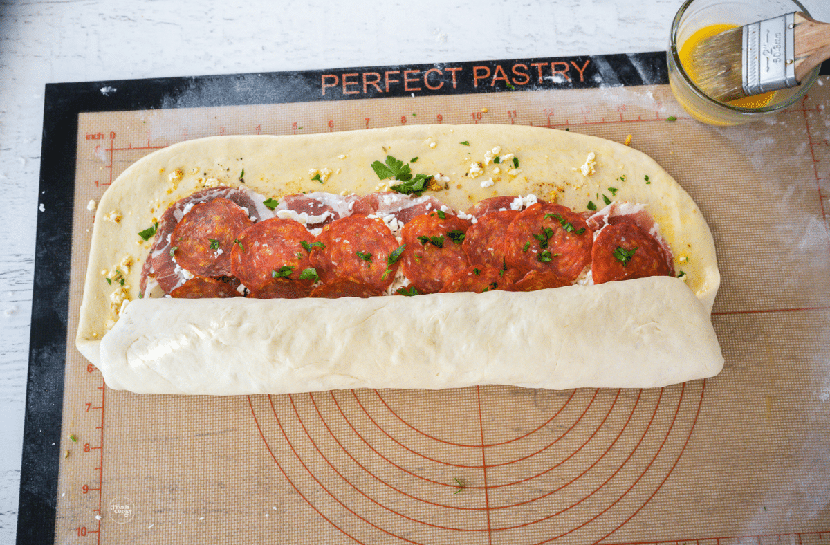 Stromboli rolled half way, folding and tucking meat in.