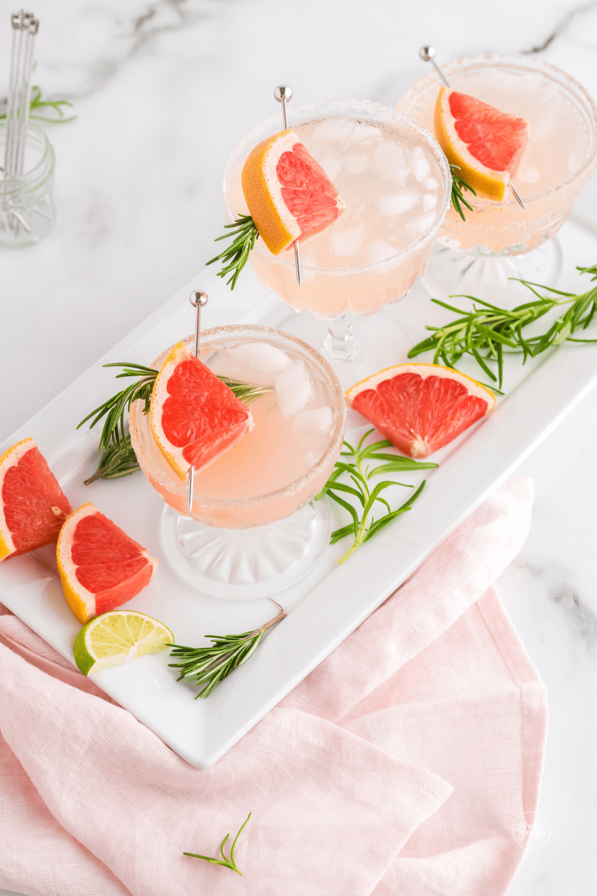 3 pretty cocktail glasses filled with light pink, grapefruit mocktail drinks.